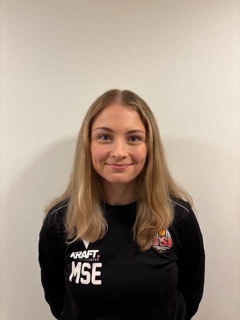 Portrett av en kvinne i svart genser mot en lys vegg.