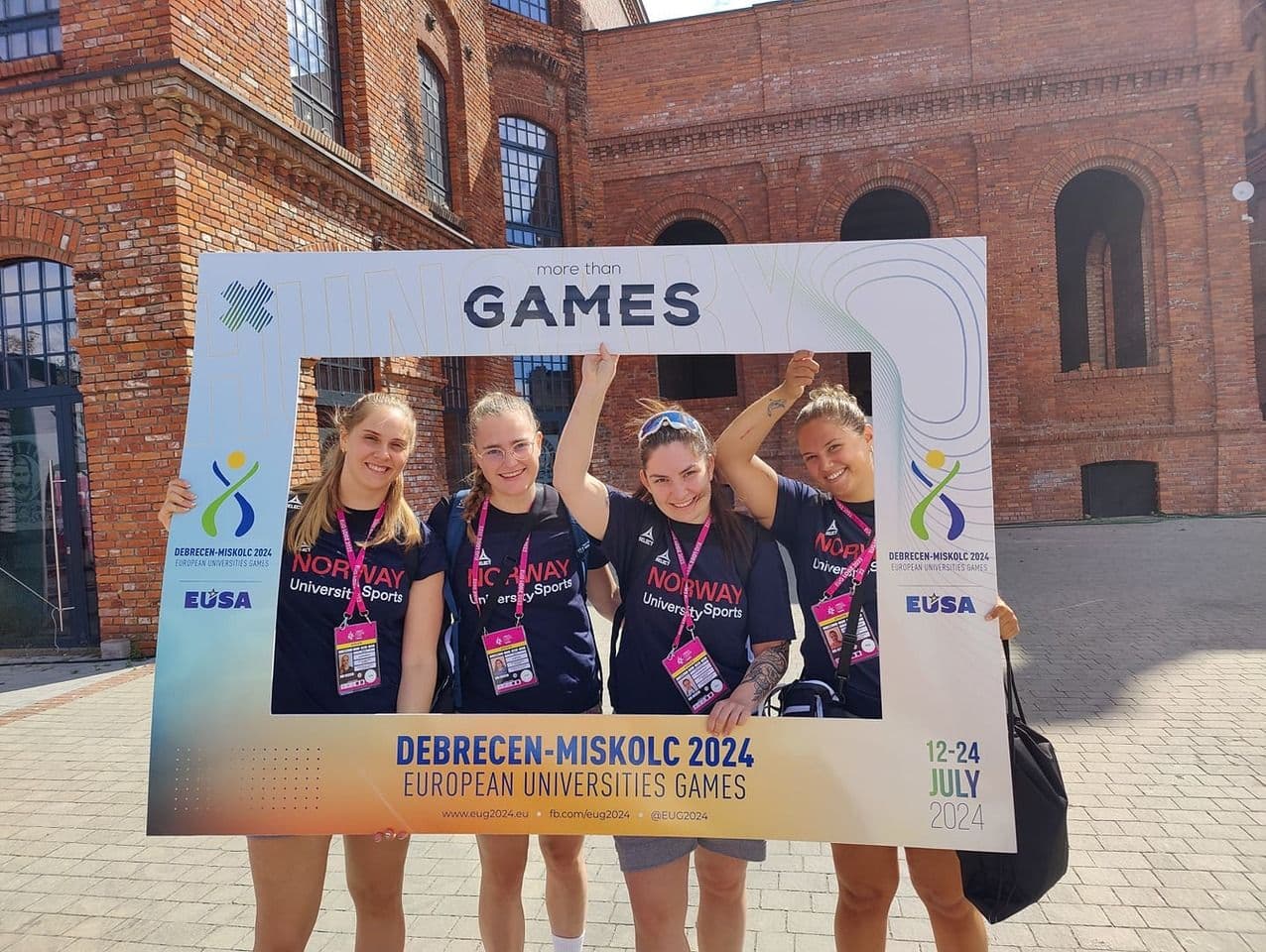 Fire kvinner holder opp en fotoramme med teksten Games foran teksten Debrecen-Miskolc 2024 European Universities Games.
