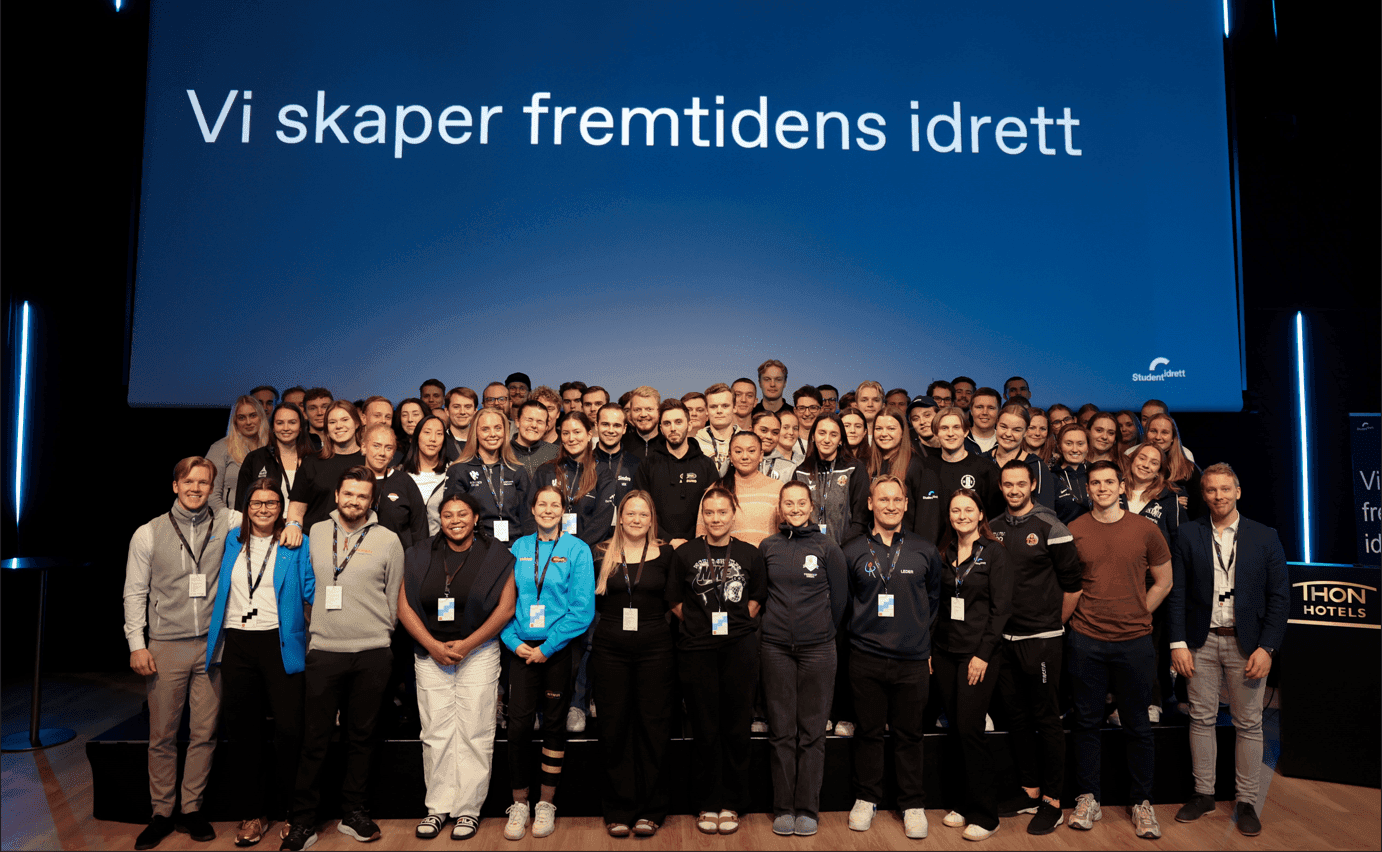 Stor gruppe deltakere samlet på en scene foran en skjerm med teksten «Vi skaper fremtidens idrett».