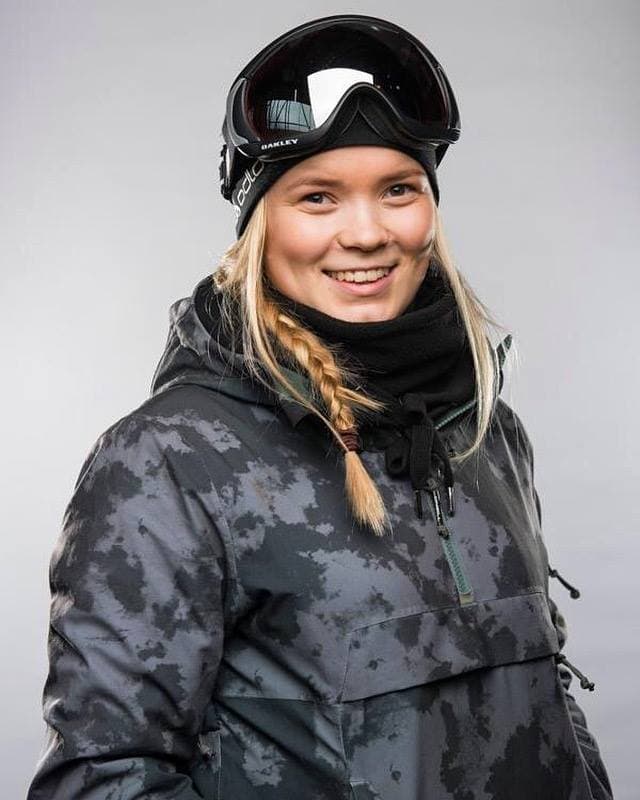 Portrett av en smilende kvinne i snowboardjakke med skibriller på hjelmen.