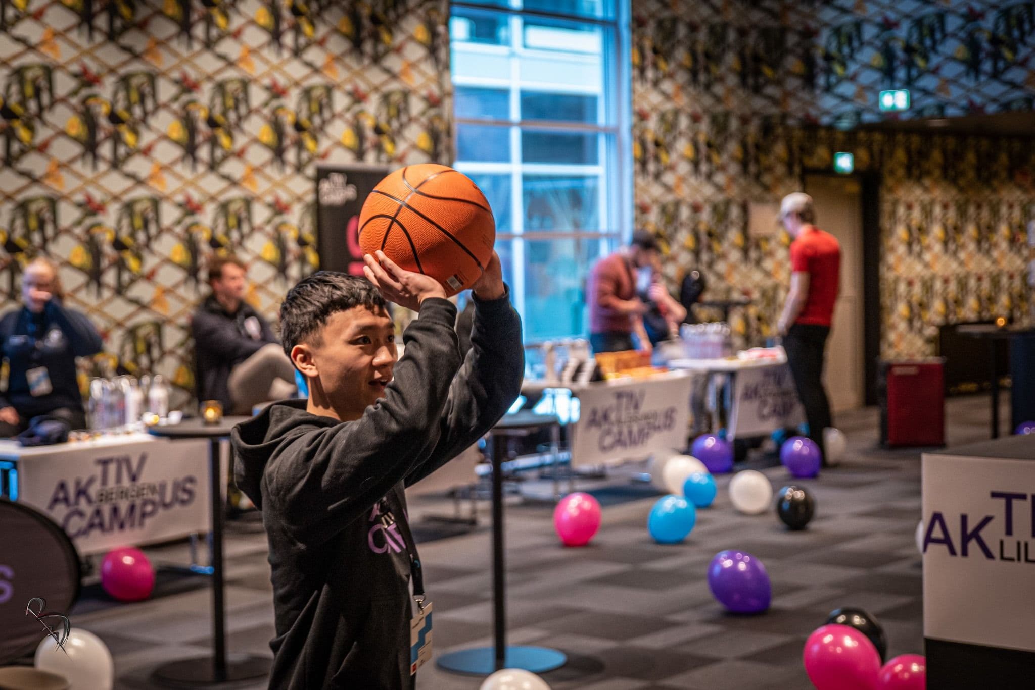En ung gutt sikter mot kurven med en basketball under et aktivitetsarrangement.