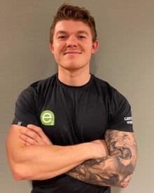 Portrett av en mann med korslagte armer i svart t-skjorte.