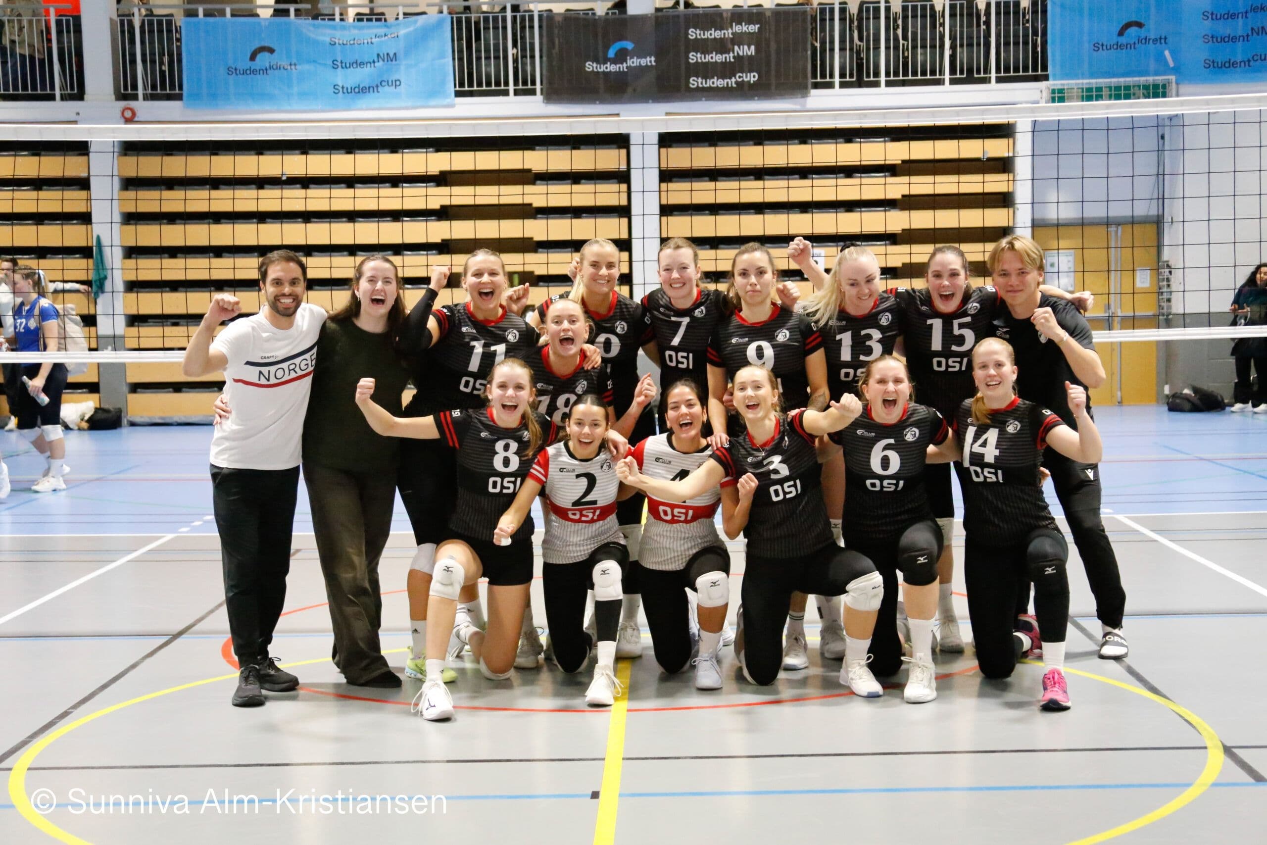 Et volleyballag fra OSI jubler samlet i en idrettshall.