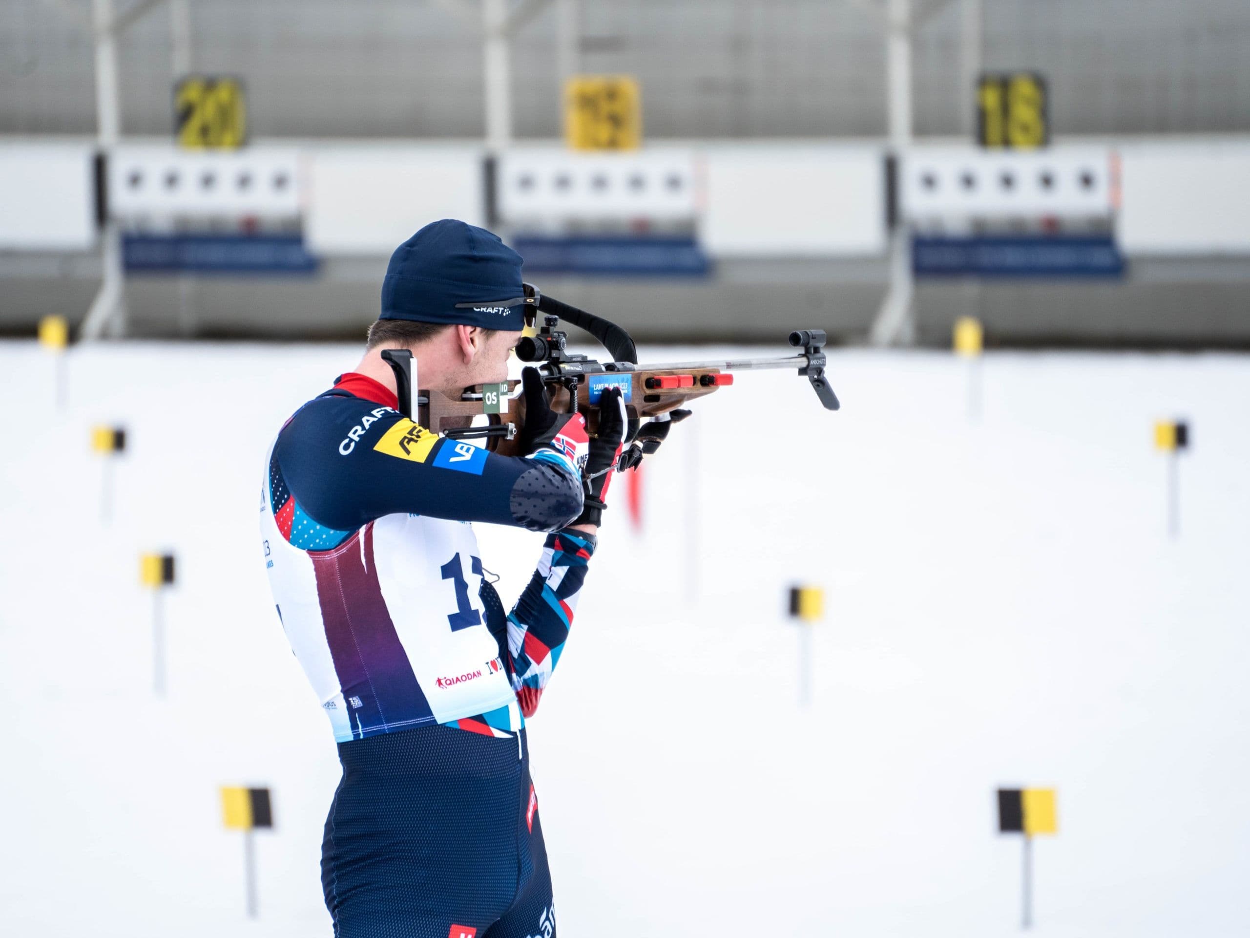 En skiskytter sikter med geværet mot blinkene på skytebanen.