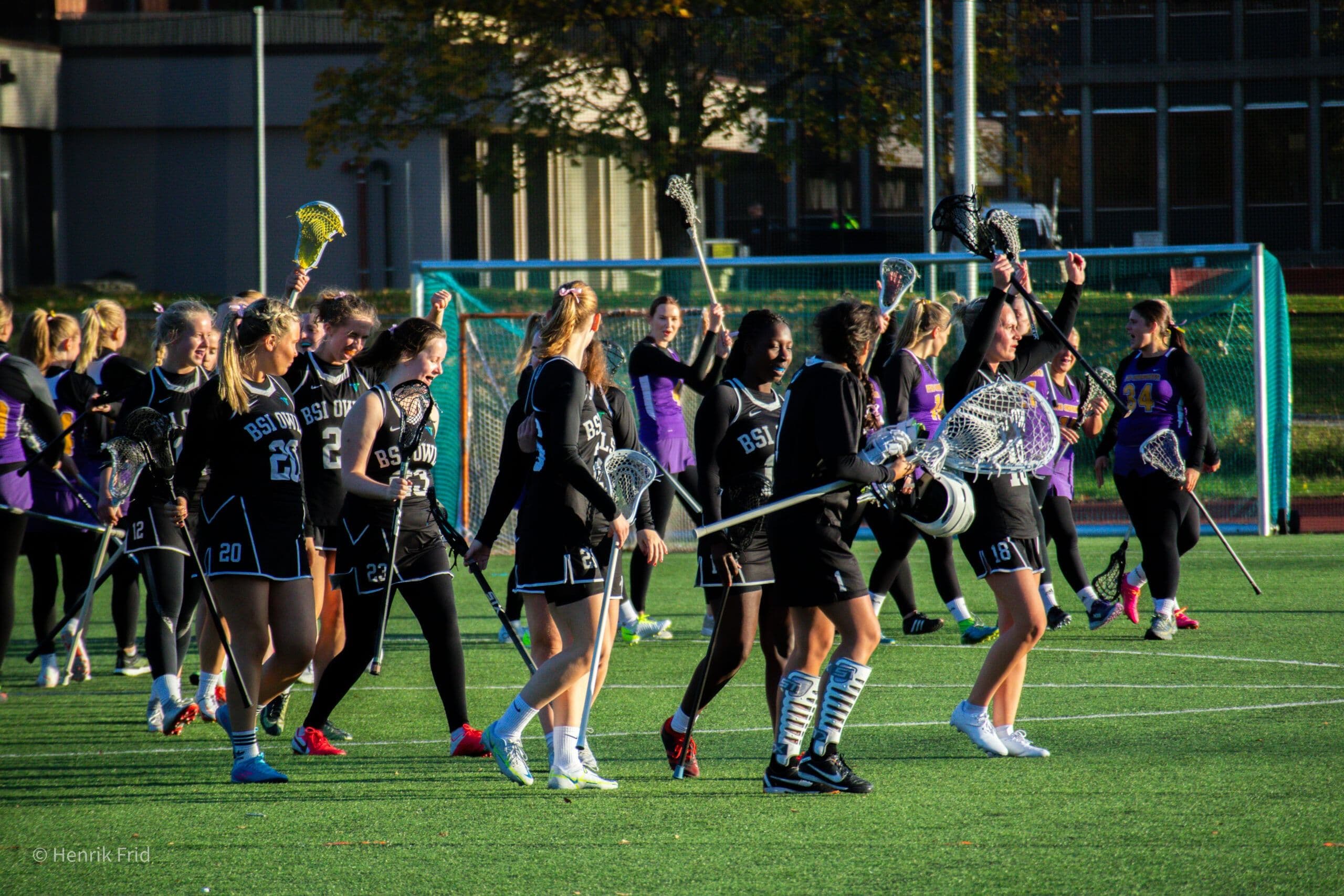 Kvinnelige lacrosselag hilser på hverandre på banen etter en kamp.