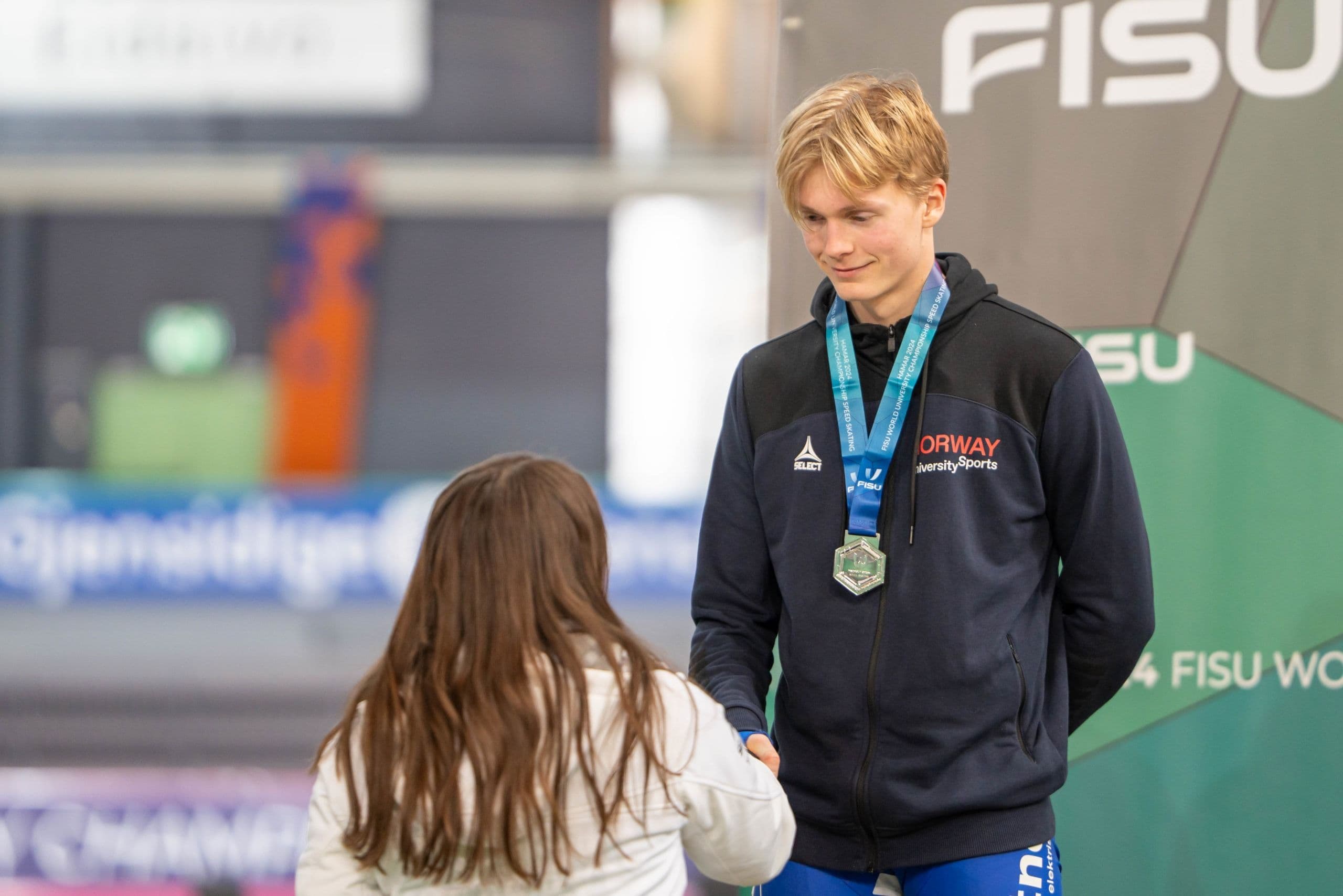 En utøver med sølvmedalje og Norway University Sports-genser tar imot gratulasjoner under et FISU-mesterskap.