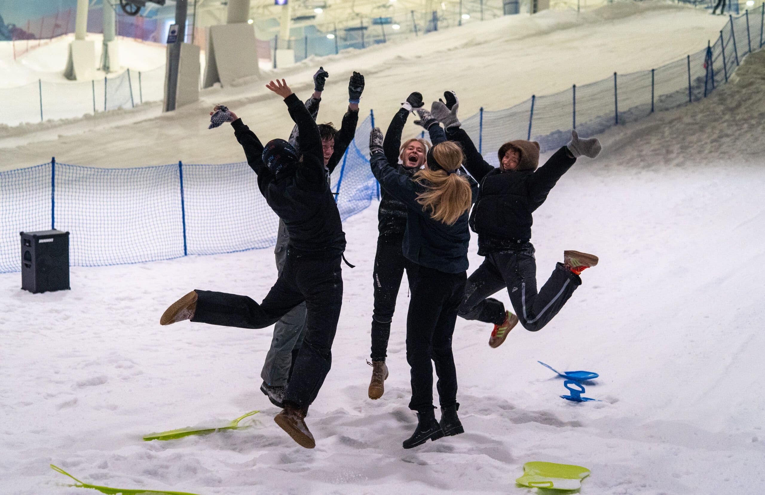 En gruppe studenter hopper av glede i en innendørs snøhall.