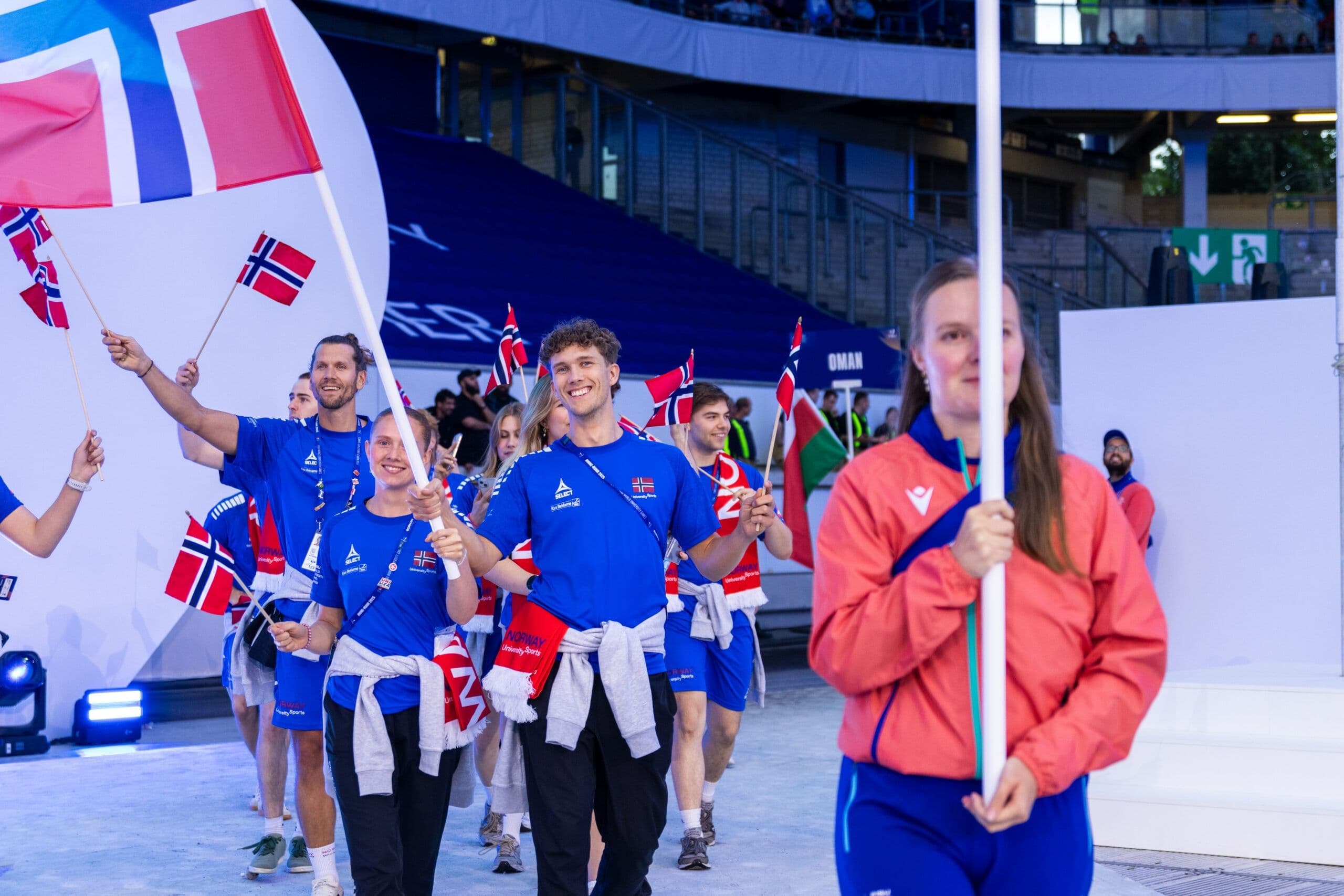 Norske utøvere med norske flagg går inn under en åpningsseremoni for et internasjonalt studentmesterskap.