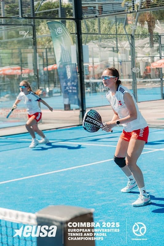 To kvinnelige padelspillere i norske drakter i spillposisjon på en blå padelbane under Coimbra 2025.
