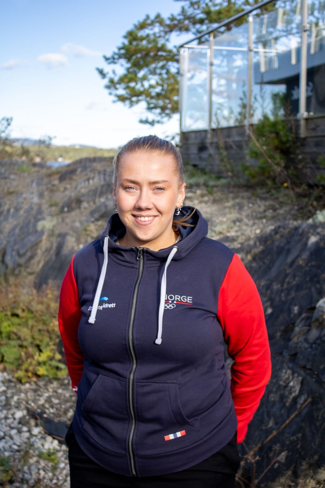 Ni studenter med klatrehjelmer holder rundt hverandre i en åpen skog.