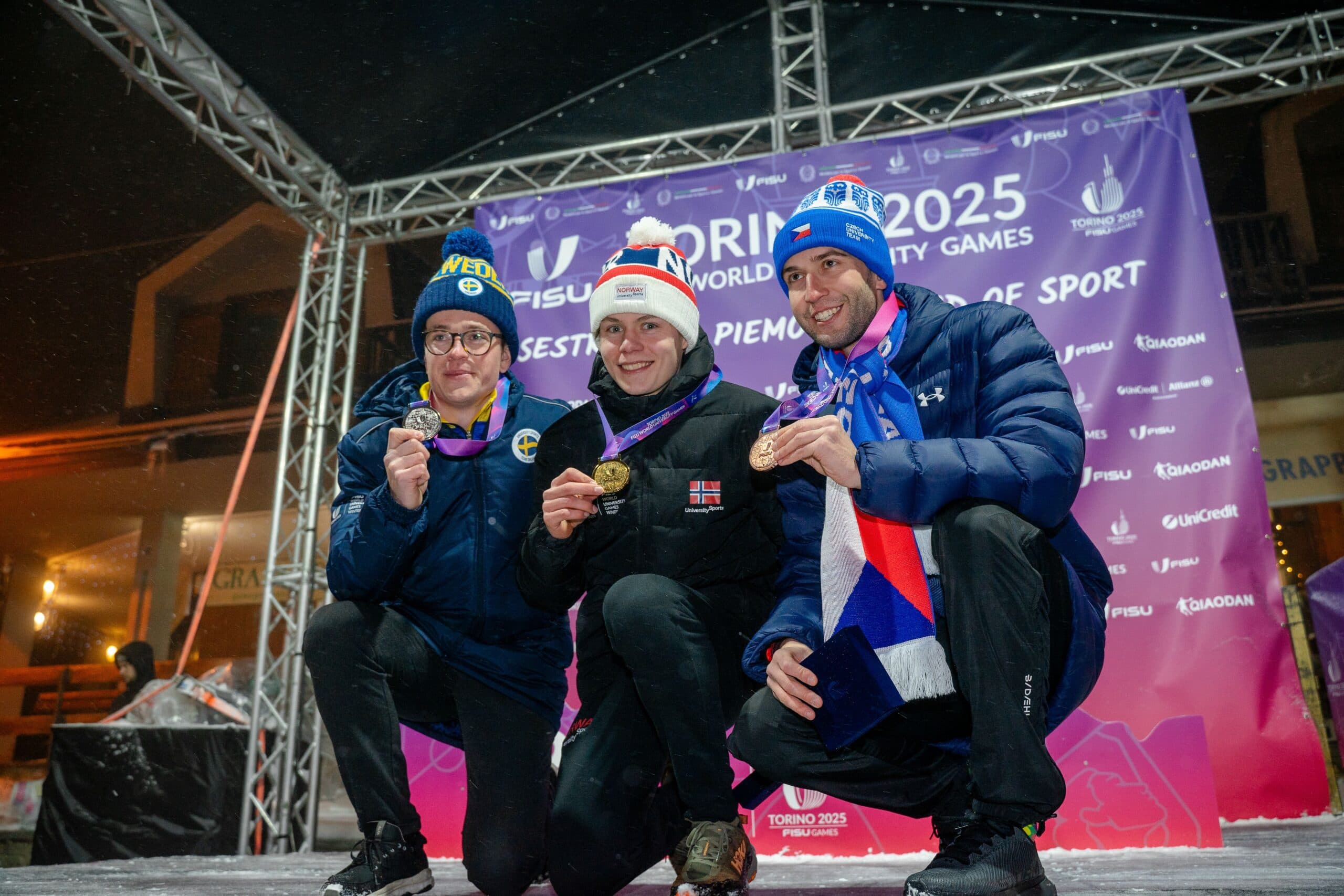 Tre utøvere viser fram medaljene sine på en scene under Torino 2025 World University Games.