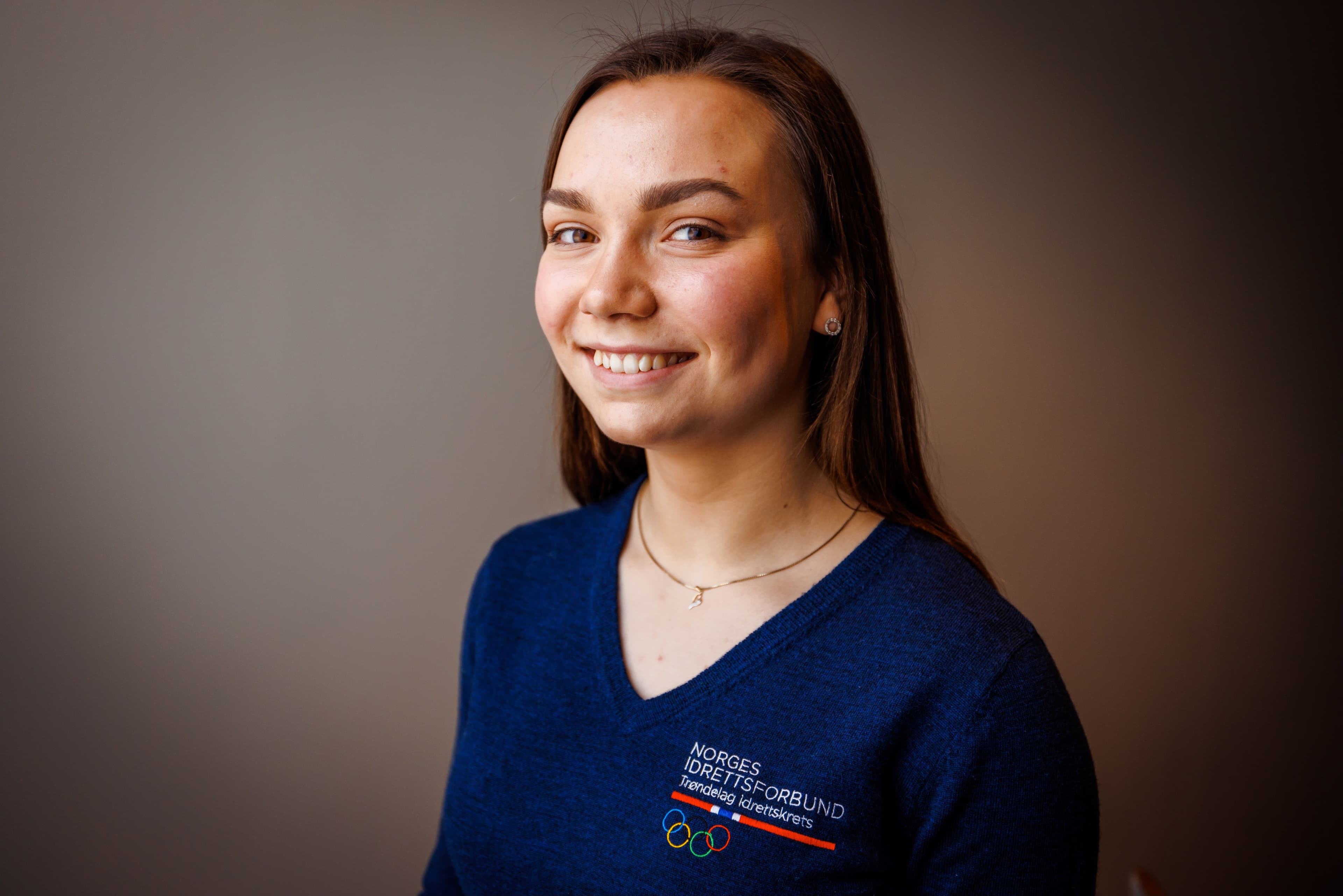 Portrett av en smilende ung kvinne i blå genser med logo for Norges idrettsforbund.