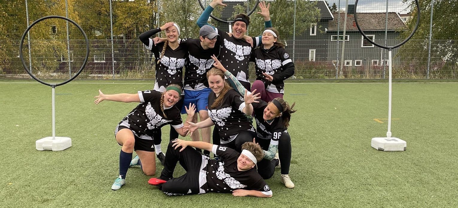 Et quadball-lag poserer og jubler på en kunstgressbane foran målringene.