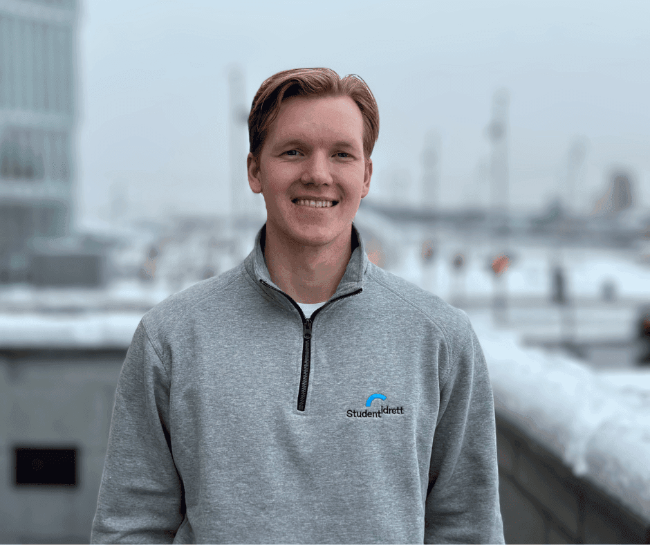Portrett av en smilende mann i grå Studentidrett-genser utendørs om vinteren.